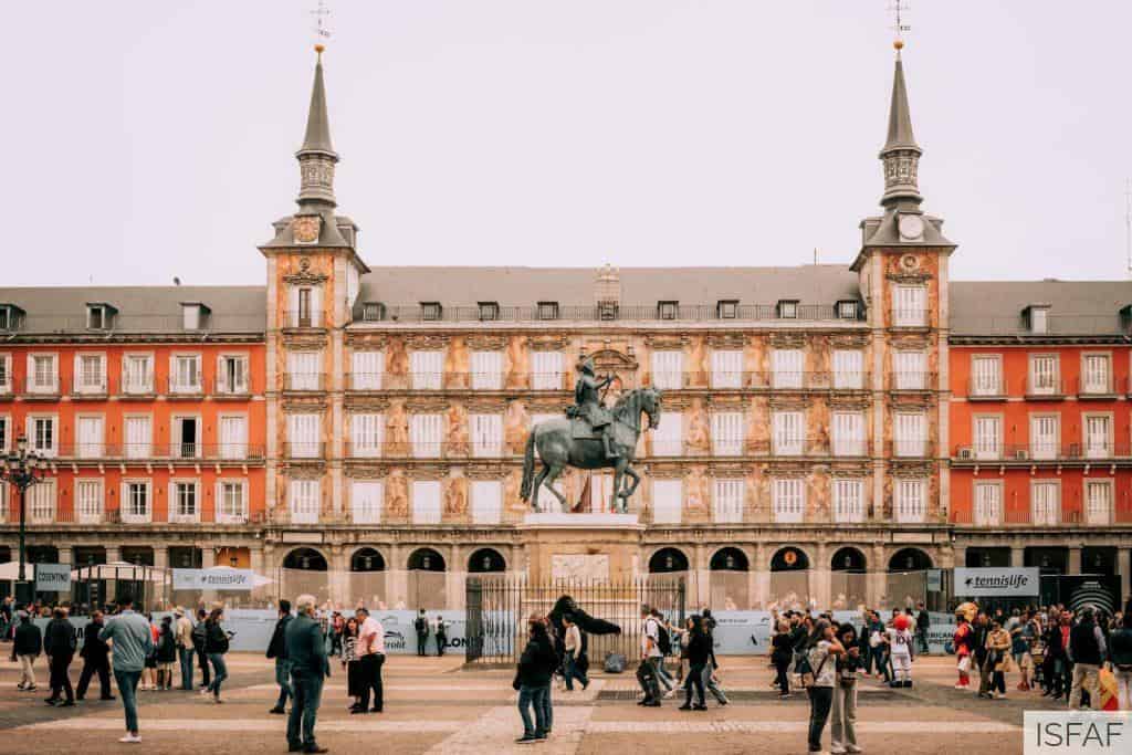 People are walking around a plaza with a statue in the middle