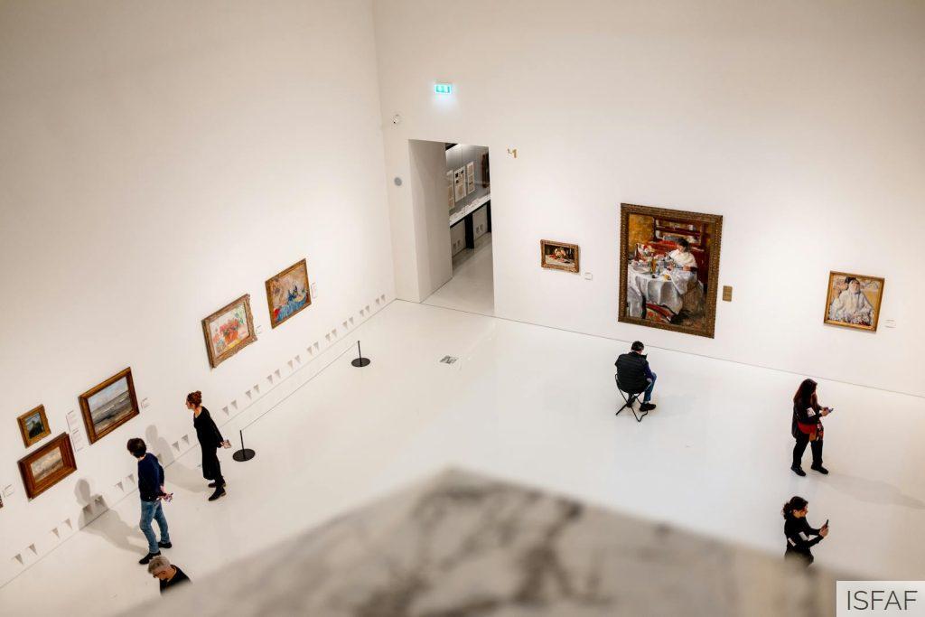 People are looking at paintings in an art museum