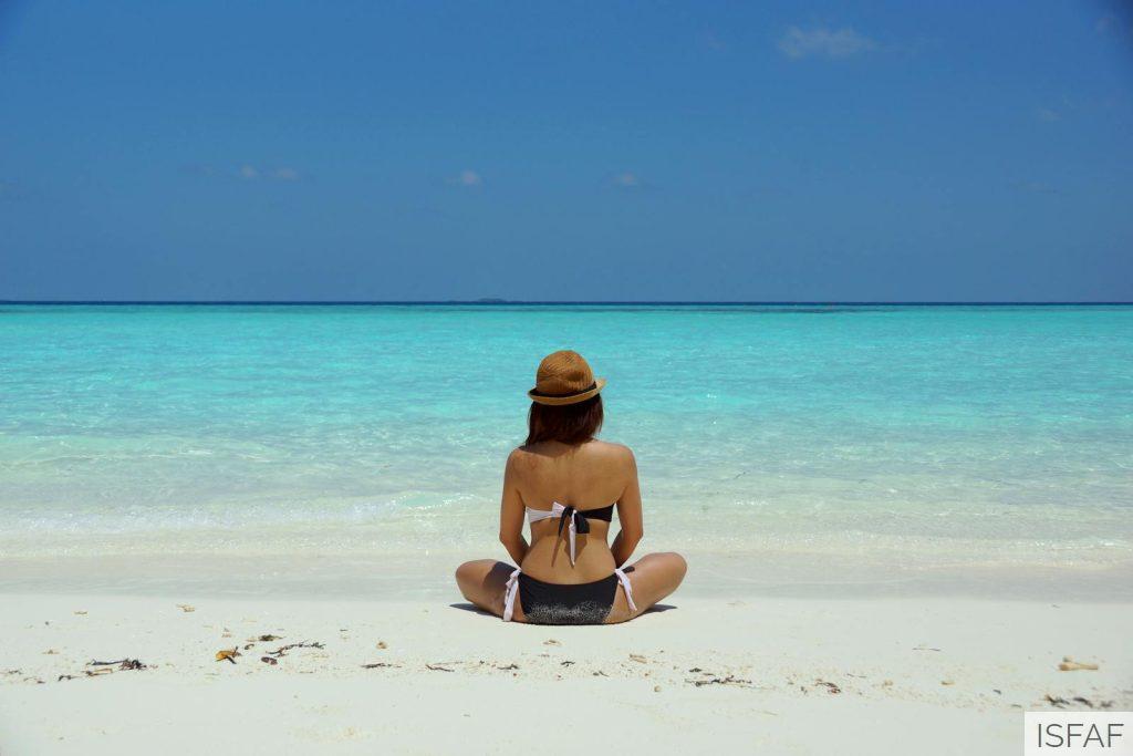 Woman Wearing Black and White Brassiere Sitting on White Sand